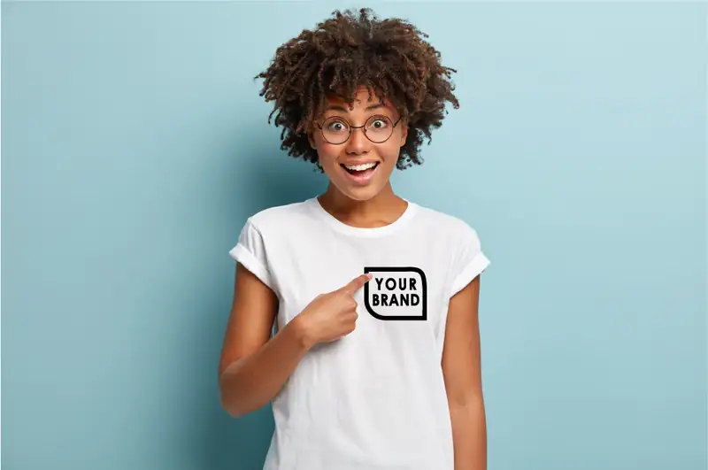 Woman pointing to Your Brand artwork on a white T-shirt